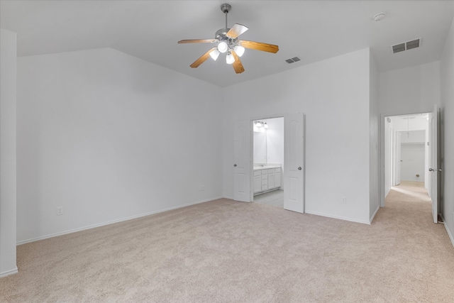 unfurnished bedroom with visible vents, light carpet, lofted ceiling, and ensuite bathroom