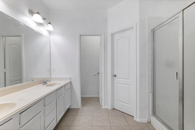 bathroom featuring baseboards, double vanity, a stall shower, tile patterned floors, and a sink