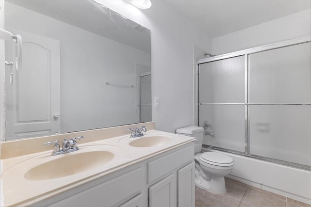 bathroom with tile patterned floors, toilet, double vanity, and a sink