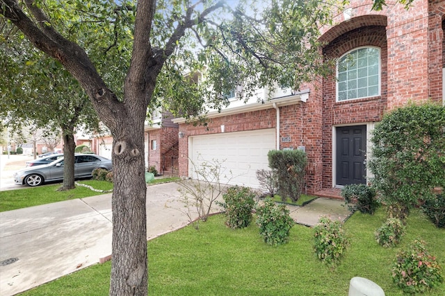 view of front of property with brick siding, driveway, an attached garage, and a front lawn