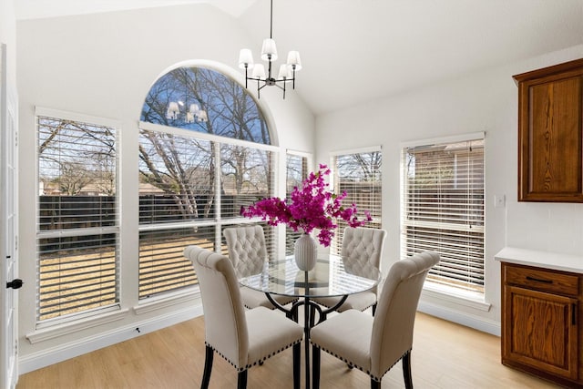 dining room featuring a notable chandelier, high vaulted ceiling, and light wood-style floors