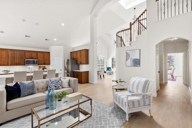 living area with visible vents, light wood-style floors, and arched walkways