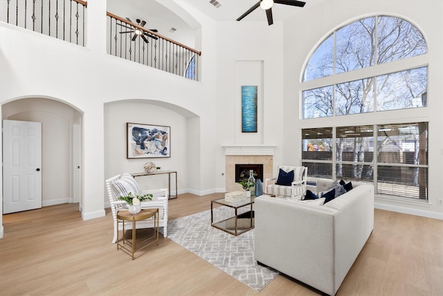 living room with a fireplace, a ceiling fan, and wood finished floors