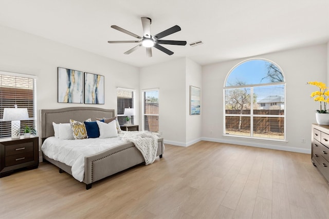 bedroom with ceiling fan, light wood-style floors, visible vents, and baseboards