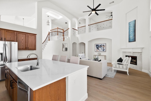 kitchen featuring light wood finished floors, a high end fireplace, stainless steel appliances, a sink, and open floor plan