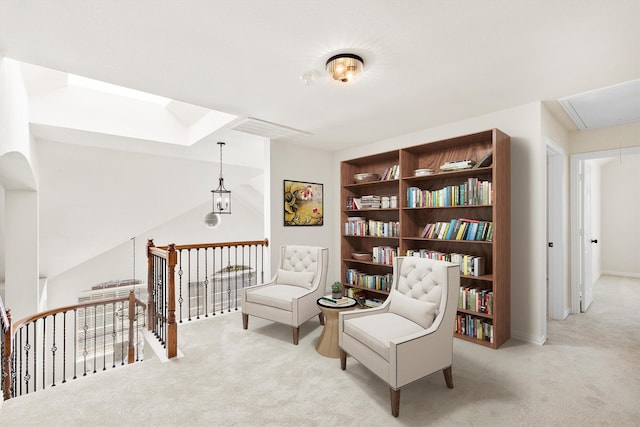 living area with visible vents, an upstairs landing, carpet, and attic access