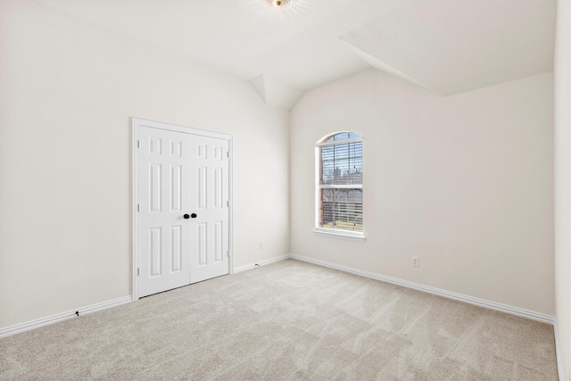 unfurnished bedroom with vaulted ceiling, carpet, baseboards, and a closet