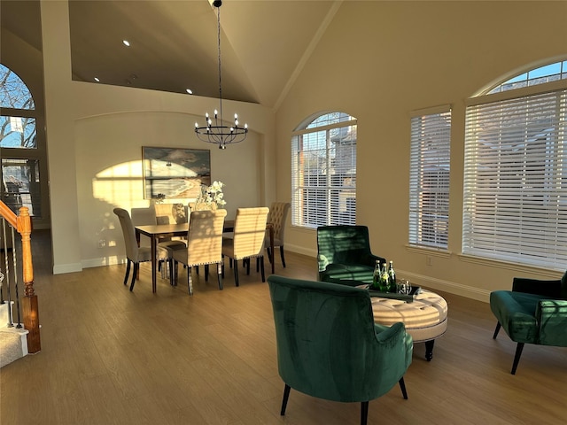 dining room featuring wood finished floors, baseboards, high vaulted ceiling, stairs, and a notable chandelier