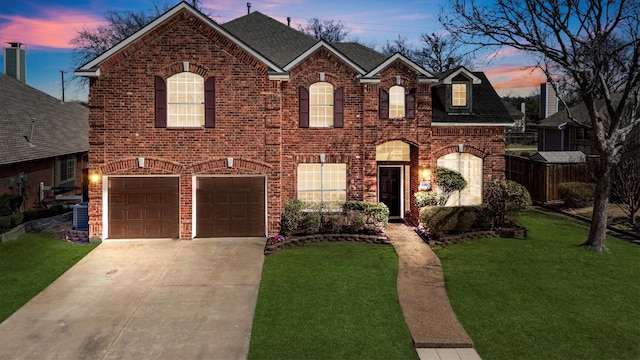 view of front of home with a yard, roof with shingles, concrete driveway, a garage, and brick siding