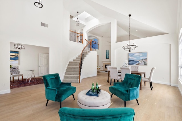 sitting room featuring light wood finished floors, visible vents, stairway, and a notable chandelier