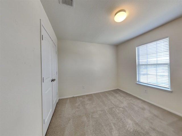 unfurnished bedroom with visible vents, baseboards, and light colored carpet