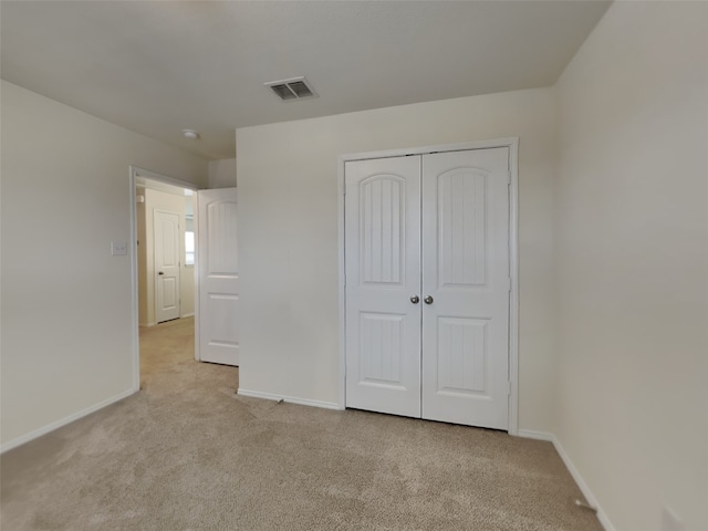 unfurnished bedroom featuring baseboards, visible vents, a closet, and light carpet