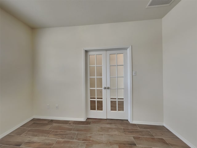 spare room featuring french doors, visible vents, and baseboards