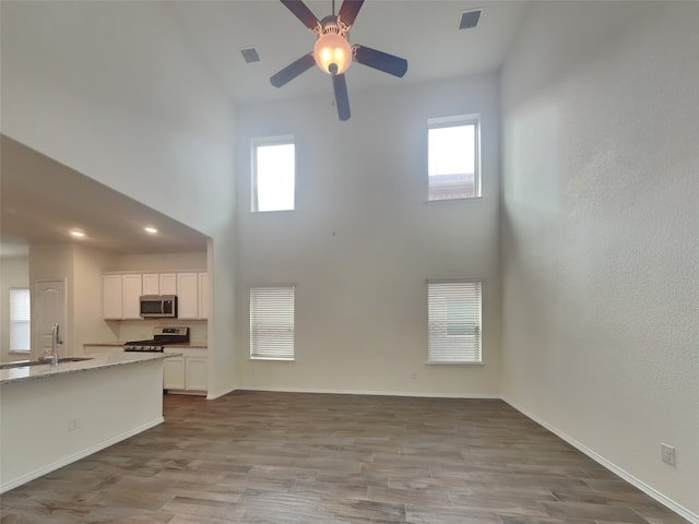 unfurnished living room with a sink, visible vents, plenty of natural light, and a high ceiling