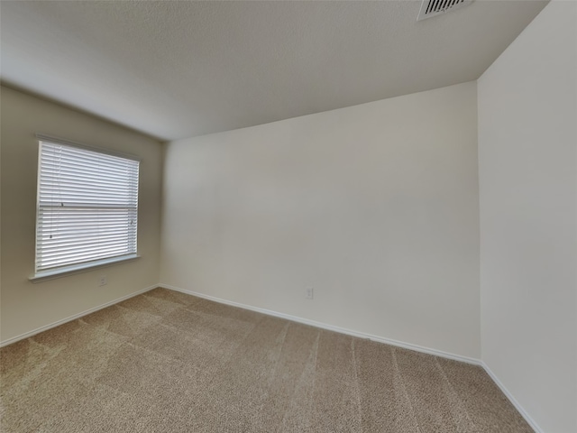 unfurnished room with a textured ceiling, baseboards, visible vents, and light carpet