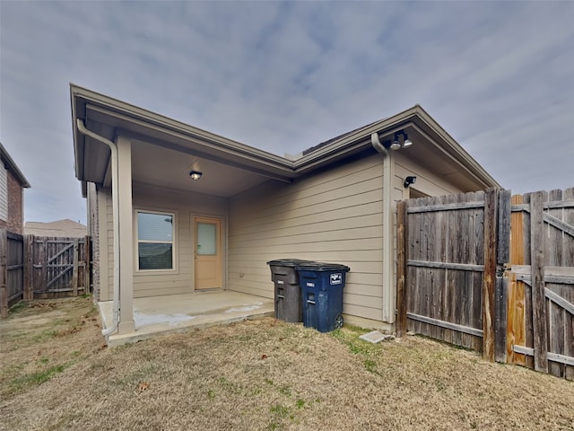 rear view of house featuring a fenced backyard, a patio, and a gate