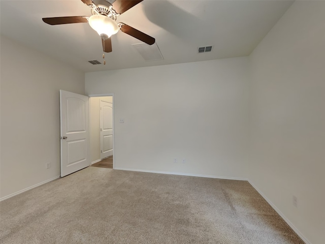 carpeted spare room with visible vents, baseboards, and a ceiling fan