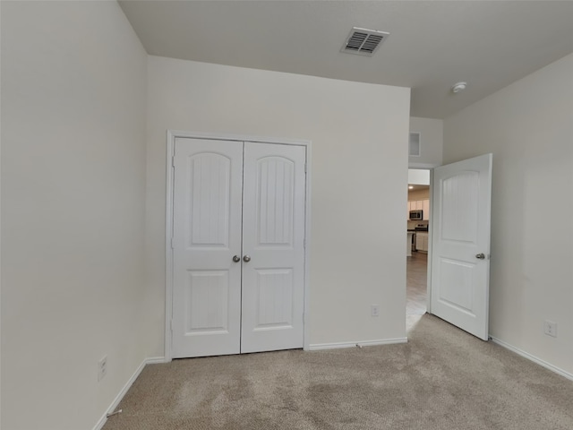 unfurnished bedroom with visible vents, baseboards, a closet, and carpet flooring