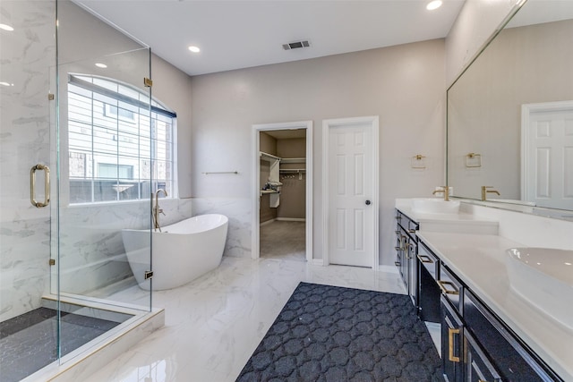 bathroom featuring visible vents, marble finish floor, a marble finish shower, double vanity, and a soaking tub