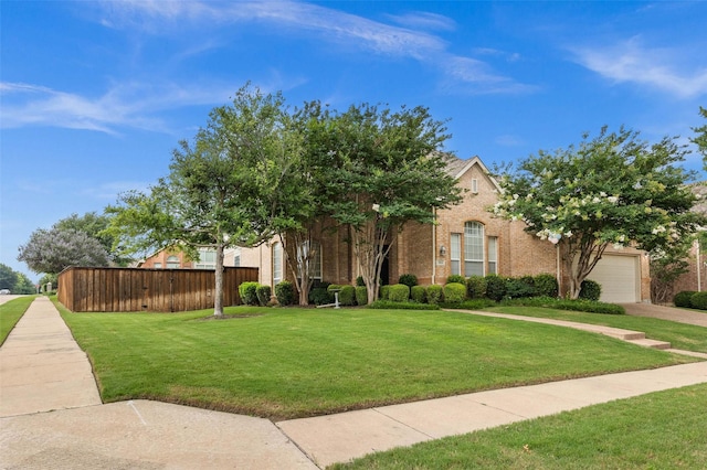 view of front of house featuring a front lawn, an attached garage, fence, and brick siding