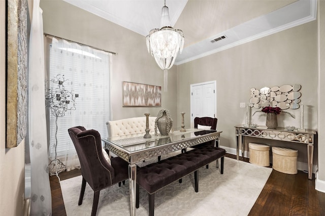 dining space featuring baseboards, visible vents, wood-type flooring, crown molding, and a notable chandelier