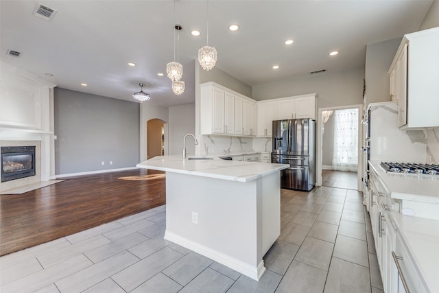 kitchen with visible vents, open floor plan, appliances with stainless steel finishes, a peninsula, and arched walkways