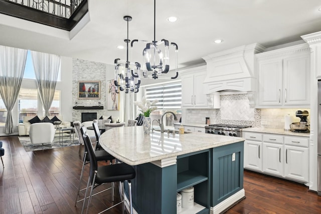 kitchen featuring custom exhaust hood, open shelves, a fireplace, a sink, and a notable chandelier