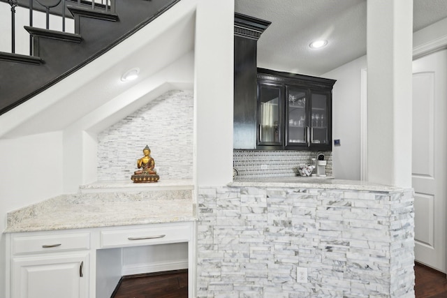 bar featuring decorative backsplash, a textured ceiling, and dark wood-type flooring