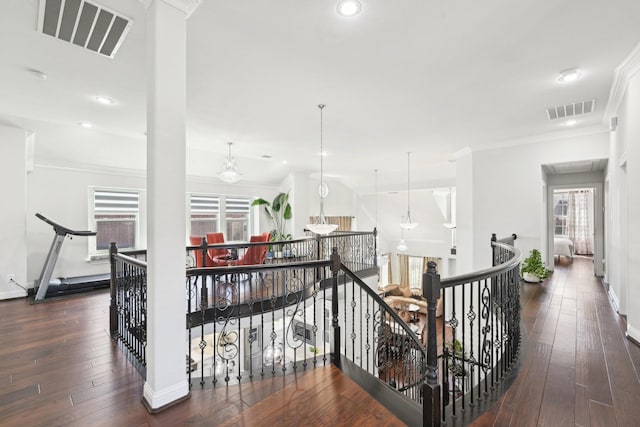 hallway with visible vents, an upstairs landing, wood-type flooring, and ornamental molding