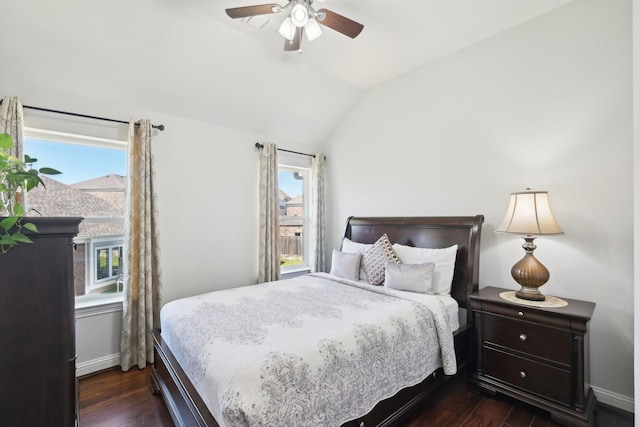 bedroom with ceiling fan, multiple windows, dark wood-style floors, and vaulted ceiling