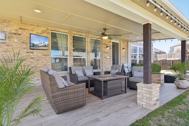 view of patio featuring an outdoor living space, a wooden deck, fence, and ceiling fan