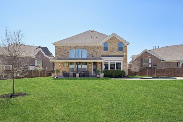 rear view of property with brick siding, a lawn, a patio, and a fenced backyard