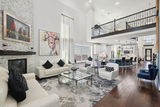 living area featuring a stone fireplace, dark wood-type flooring, a high ceiling, and ornamental molding