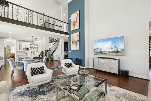 living area featuring stairway, baseboards, visible vents, and wood finished floors