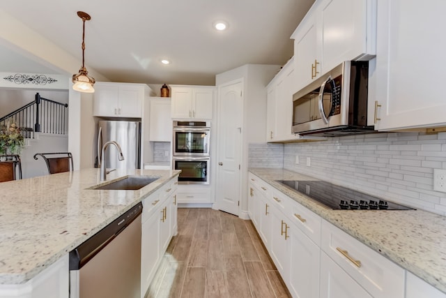 kitchen with backsplash, white cabinets, stainless steel appliances, and a sink