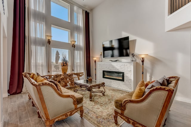 living area with a fireplace, a high ceiling, and wood finished floors