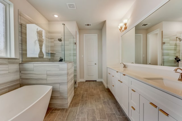 bathroom with a sink, visible vents, a shower stall, and a freestanding tub