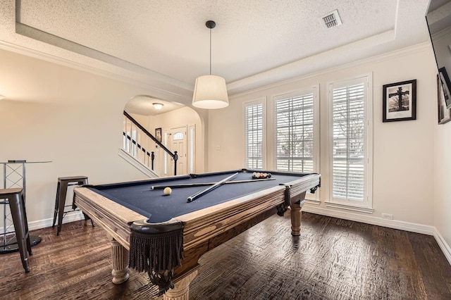 recreation room featuring dark wood-style floors, visible vents, arched walkways, a textured ceiling, and a raised ceiling