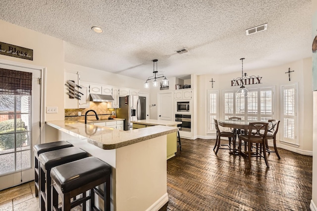 kitchen featuring under cabinet range hood, tasteful backsplash, visible vents, and appliances with stainless steel finishes