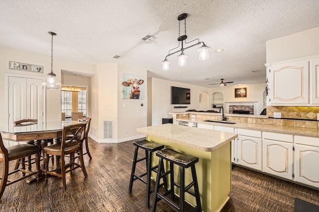 kitchen featuring a peninsula, a fireplace, visible vents, and a sink