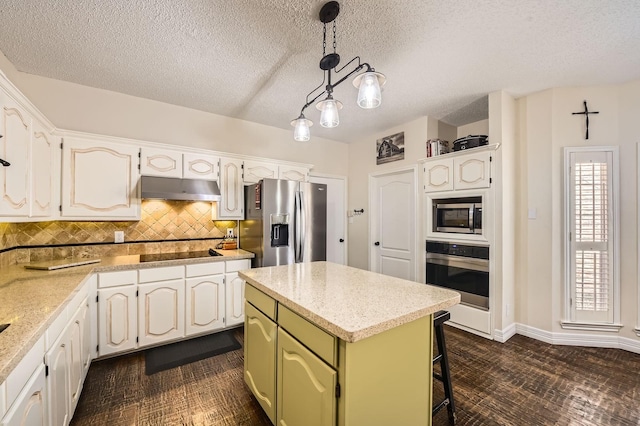 kitchen featuring tasteful backsplash, a kitchen island, green cabinets, under cabinet range hood, and appliances with stainless steel finishes