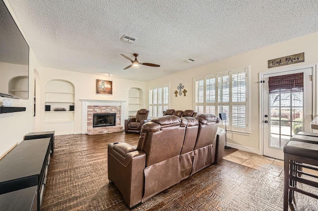 living room with built in features, a fireplace, and visible vents