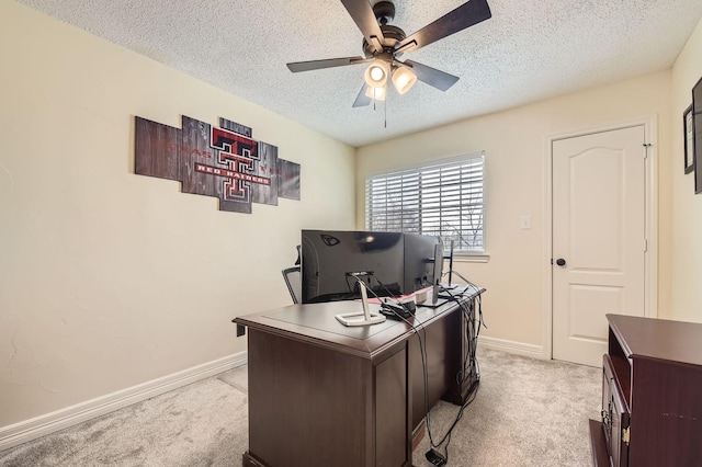 office space featuring a textured ceiling, a ceiling fan, baseboards, and light carpet