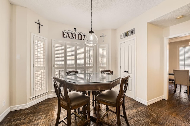 dining area with a textured ceiling, dark wood-type flooring, and baseboards