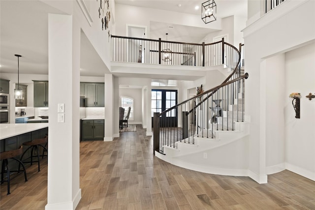 foyer with stairway, baseboards, light wood-style floors, and a towering ceiling