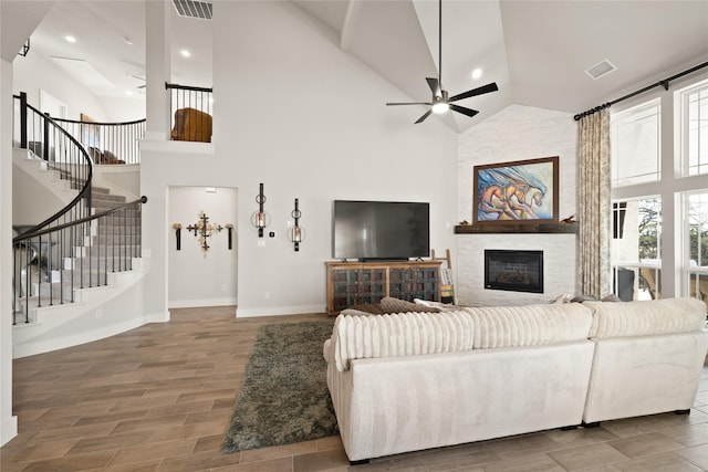 living area featuring visible vents, stairway, a fireplace, and ceiling fan