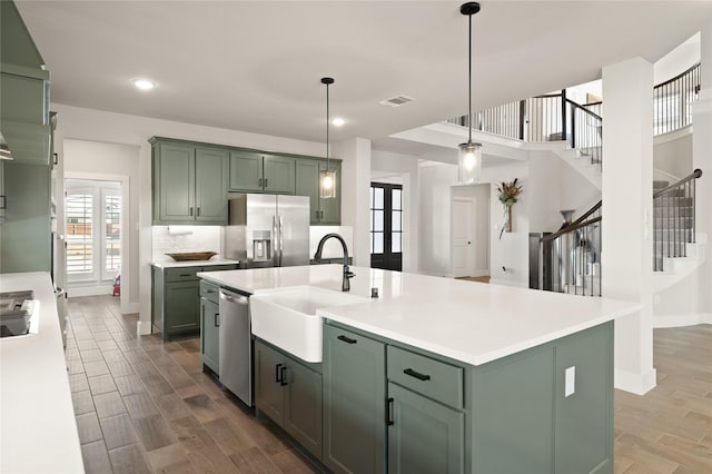 kitchen with stainless steel appliances, green cabinets, and a sink