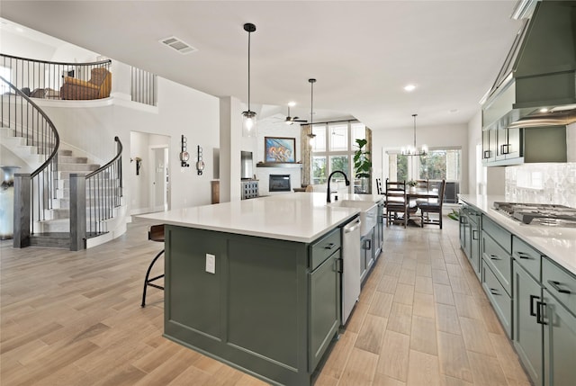 kitchen with visible vents, green cabinets, custom exhaust hood, a glass covered fireplace, and stainless steel appliances