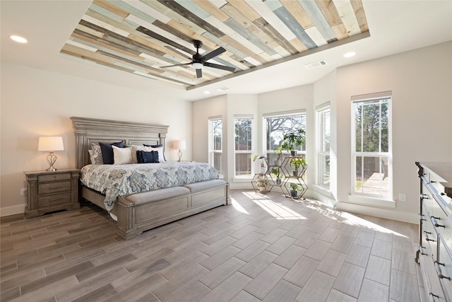 bedroom with visible vents, recessed lighting, a tray ceiling, and wood tiled floor