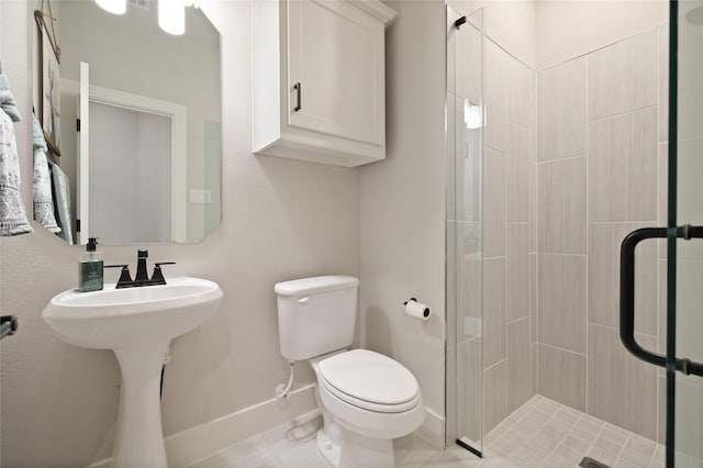 full bathroom with a shower stall, toilet, baseboards, and a sink